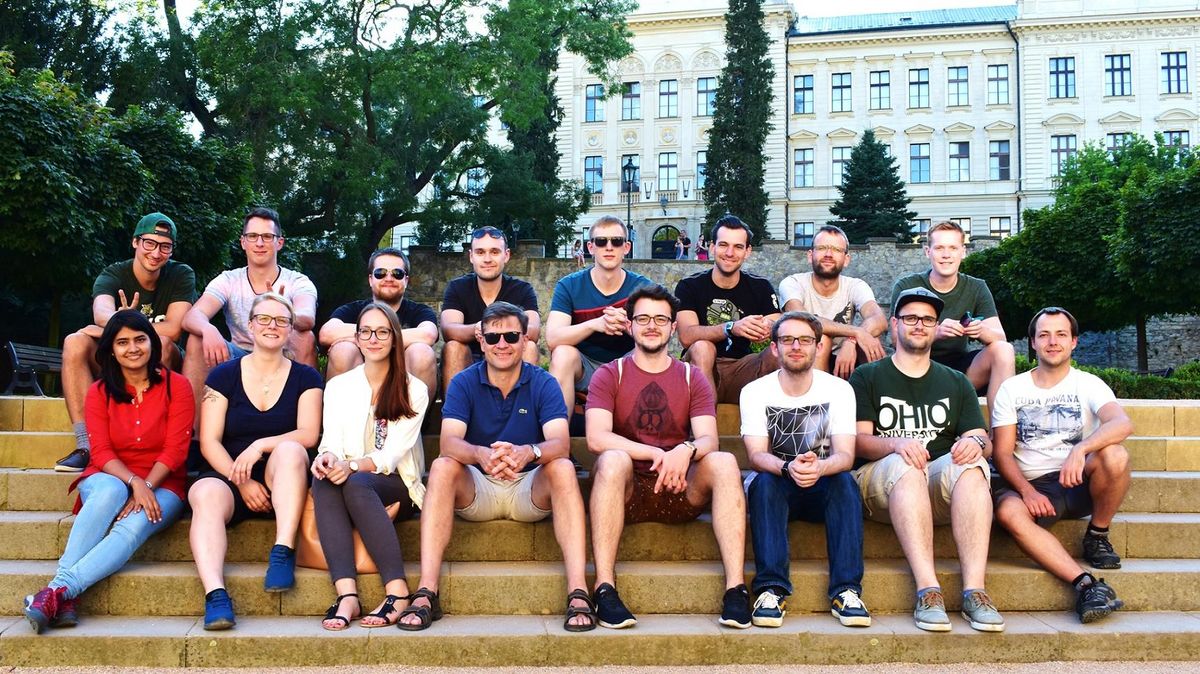 Das Bild zeigt das Team AK Schneider sitzend auf einer Treppe in Prag