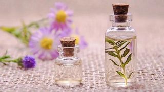Bild mit Lavendel- und Kornblumenzweig im Hintergrund, 2 Flaschen mit Öl im Vordergrund, eine der beíden Flaschen enthält einen weiteren Zweig, Pflanze unbekannt, Foto: Pixabay 